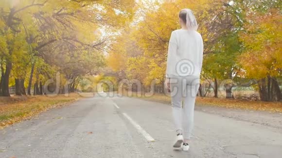 在秋天的大自然中在沥青跑道上系鞋带的跑步者年轻的女人准备开始跑步女孩从事户外运动视频的预览图
