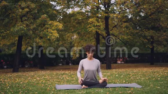 灵活的年轻女士坐在垫子上瑜伽姿势享受新鲜的空气和平和放松城市健康生活方式视频的预览图