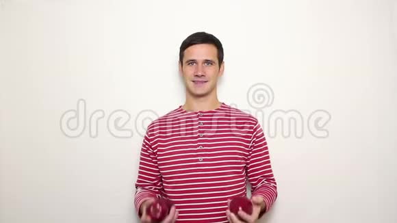 年轻的帅哥穿着一件条纹毛衣笑得很宽手里拿着三个红苹果视频的预览图