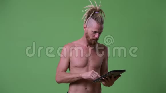 英俊肌肉发达长着长胡子戴着可怕眼镜的男子使用的是赤膊平板电脑视频的预览图