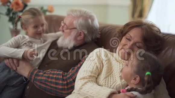 快乐的胡子爷爷和可爱的祖母拥抱和交谈他们的小有趣的孙女视频的预览图