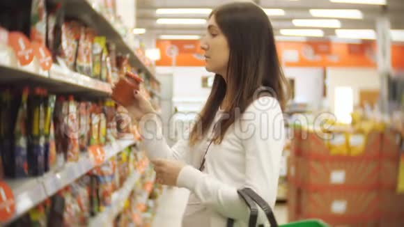 年轻女子站在超市手里的番茄酱瓶里视频的预览图