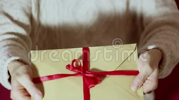 漂亮的女孩拿着一个带有红色丝带的礼物信封漂亮的女孩手里拿着一个带有红丝带的礼物信封视频的预览图