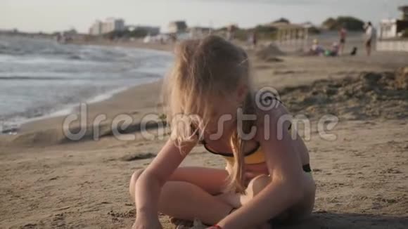 小女孩在海滩上玩沙子享受一个可爱的假期视频的预览图