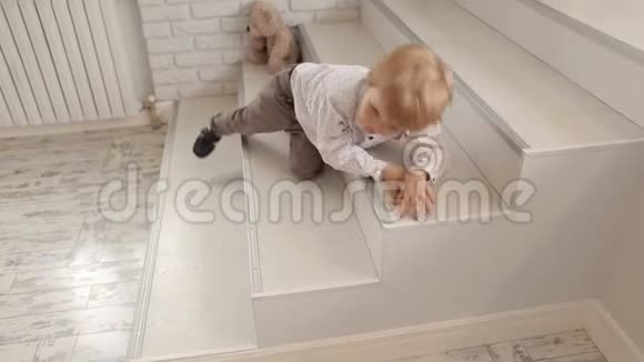 一个小可爱的男孩躺在一个明亮时尚的公寓的台阶上视频的预览图