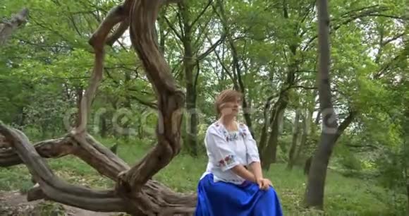 穿着民间服饰的女士坐在森林里休息视频的预览图