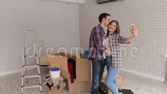 幸福的夫妻在他们的新公寓里自拍一个幸福的男人吻他的妻子视频的预览图