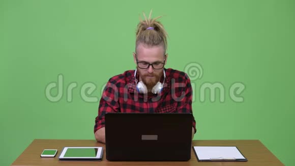 快乐留胡子的嬉皮士男子视频通话时手机工作在木制桌子视频的预览图