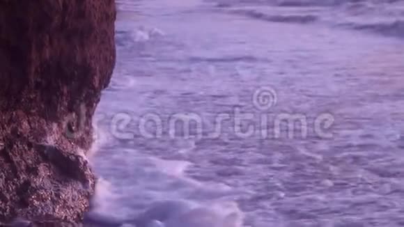 大浪带着白色的海泡在沙滩上打着湿沙粘土岩在蓝天上视频的预览图
