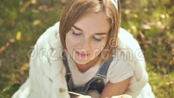 初秋一个长着雀斑的快乐女孩在公园里玩一个包裹着白色美利奴格子的蒲公英视频的预览图