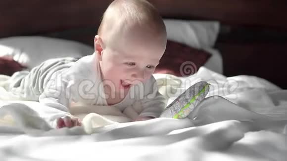 可爱的小男孩在床上放松和玩耍快乐地微笑白天视频的预览图