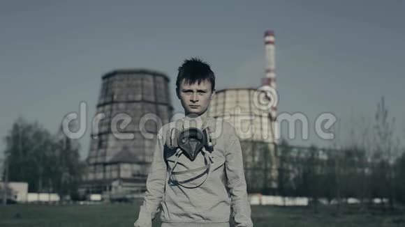 穿着防毒面具的男孩对着工厂烟囱空气污染概念视频的预览图