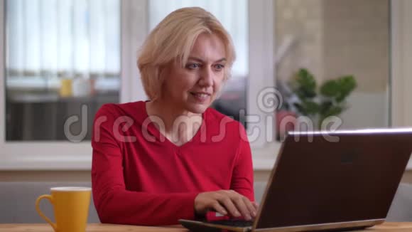 在一间舒适的公寓里一位年轻的高加索女人在室内的笔记本电脑上打字视频的预览图