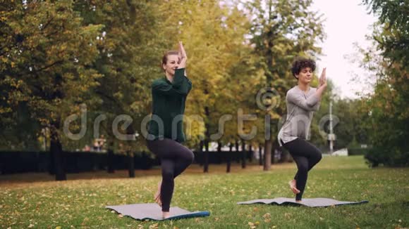 女瑜伽教练在公园教起学鹰姿势开朗的女孩在犯错误在笑视频的预览图