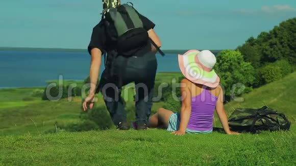 一对男女背着背包坐在山边欣赏湖景射击视频的预览图
