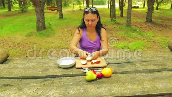 一个年轻的女人在一个公园的木桌上清理苹果从核心视频的预览图