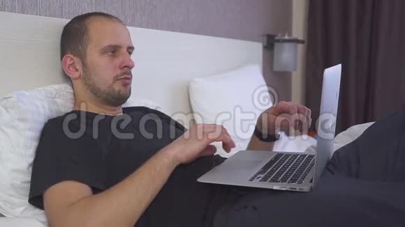 一个躺在床上用笔记本电脑工作的人真想睡觉揉揉眼睛视频的预览图