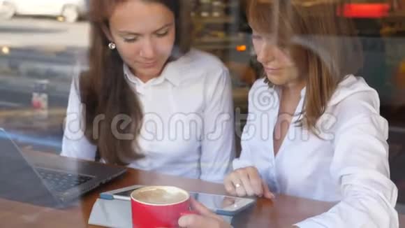 两个忙碌的女孩在咖啡馆里用触摸板和笔记本视频的预览图