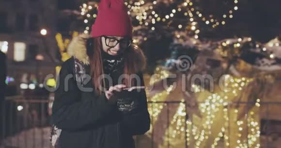 女人在城市的夜晚使用智能手机模糊的夜晚繁忙的街灯背景视频的预览图