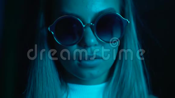 一个年轻漂亮的女孩晚上在城市的霓虹灯附近戴眼镜和漂亮镜片的嬉皮士少年视频的预览图
