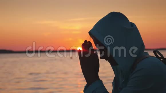 日落时分一个穿着头巾在湖边祈祷的中年妇女侧视图视频的预览图