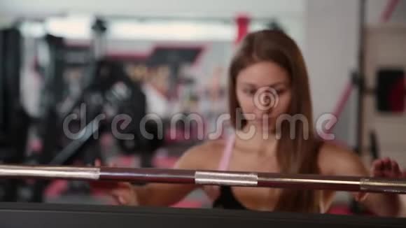 漂亮的运动女孩来到酒吧蹲在健身房视频的预览图