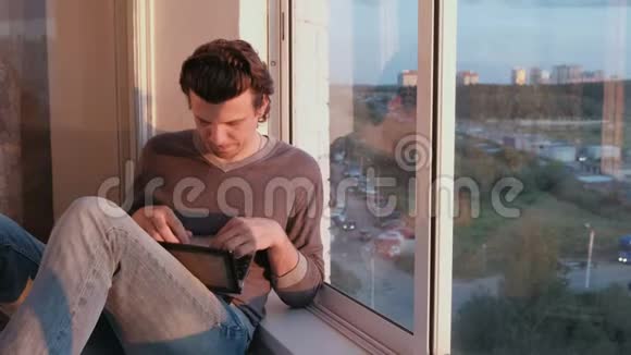 晚上日落时分坐在阳台上俯瞰城市的人在电脑上打字视频的预览图