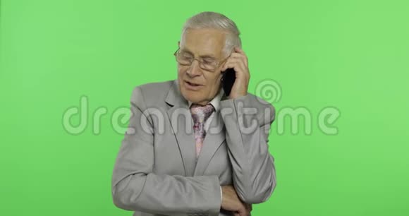 英俊的老年商人在智能手机上交谈穿西装的老头视频的预览图