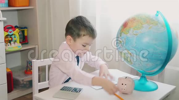 一个小男孩把他的积蓄记在计算器上然后写在笔记本上视频的预览图
