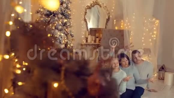 圣诞前夜在舒适的家中一家人在新年树背景下摆姿势视频的预览图