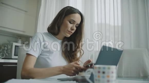 家庭厨房里的自由职业者使用手机的女性视频的预览图