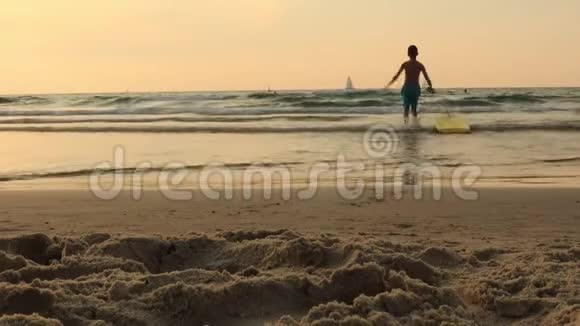 快乐男孩玩跑骑在黑板上儿童和冲浪概念日落时在海滩上冲浪视频的预览图