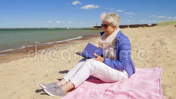 快乐的老年女性在夏日海滩读书视频的预览图