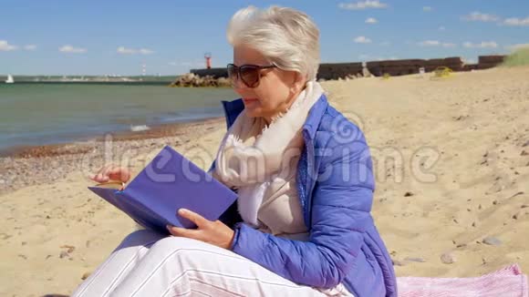 快乐的老年女性在夏日海滩读书视频的预览图