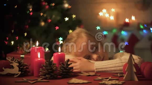 可爱的女孩睡在装饰圣诞庆典的桌子上舒适的家视频的预览图