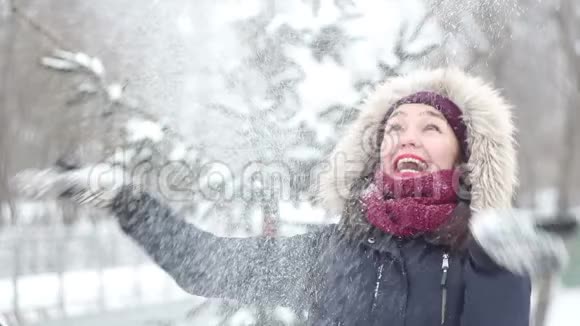 美丽的年轻女孩用手举起雪积极地表达喜悦笑着拍手视频的预览图