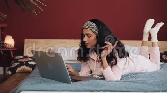 非裔美国妇女躺在床上用便携式笔记本进行互联网交流她玩得很开心很高兴视频的预览图