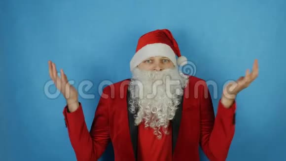 圣诞节和新年像圣诞老人一样的人在蓝色背景下感到惊讶和震惊视频的预览图