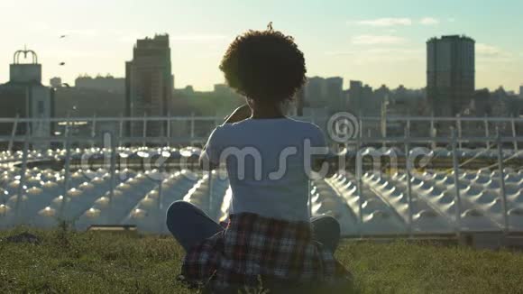 放松的非裔美国妇女坐在莲花的姿势在日落时沉思休息视频的预览图