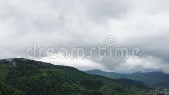 雨季时在郁郁葱葱的绿色雨云覆盖热带雨林山中的一个村庄的鸟瞰图视频的预览图