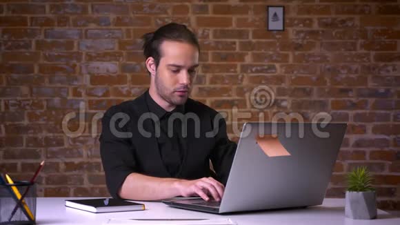 英俊的白种人男性不再使用笔记本电脑脸上带着惊讶和困惑坐着看着相机视频的预览图