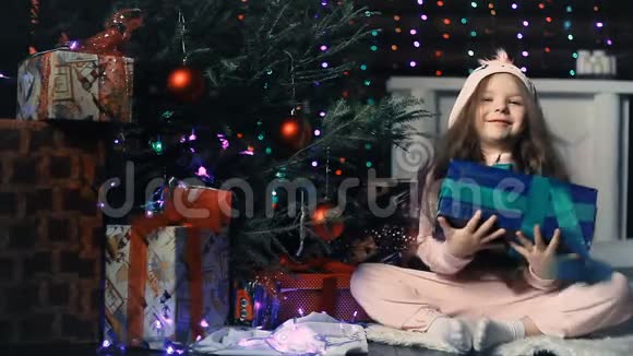 圣诞树下的一个小女孩手里拿着礼物视频的预览图