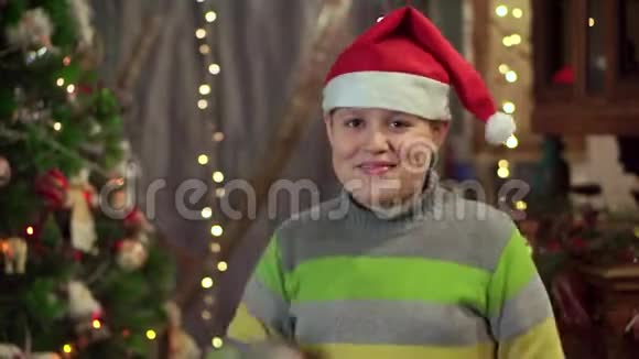 一个戴着帽子的少年圣诞老人正在圣诞树附近跳舞圣诞假期新年快乐视频的预览图