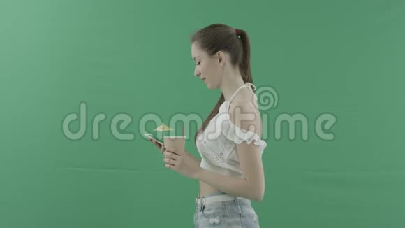 美女在绿色背景下喝鸡尾酒在智能手机上发短信视频的预览图