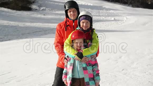 幸福的年轻家庭在滑雪服与有趣的孩子在明亮的冬天衣服手牵着手在公园里散步精彩绝伦视频的预览图