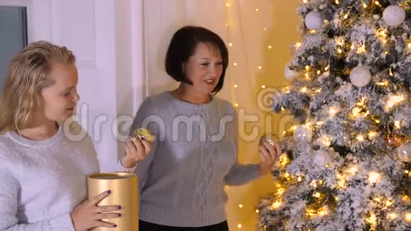 妈妈和女儿一起在假日前夕在客厅装饰圣诞树视频的预览图