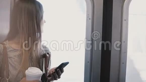 快乐美丽的微笑女商人在地铁列车上使用智能手机购物应用程序站在入口门窗视频的预览图