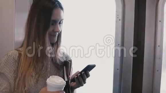 乘坐地铁列车在门口用信使看智能手机的快乐轻松迷人的女千禧女孩视频的预览图