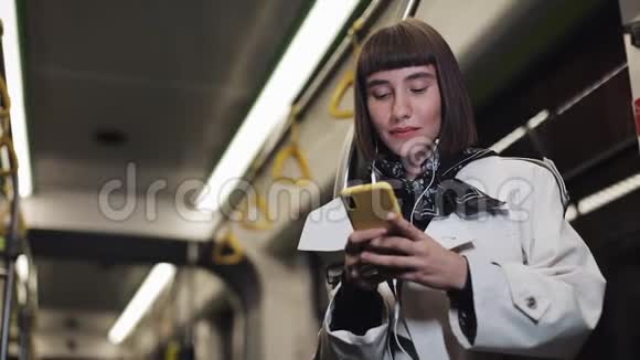 乘坐公共交通工具听音乐和浏览黄色耳机的美女画像视频的预览图