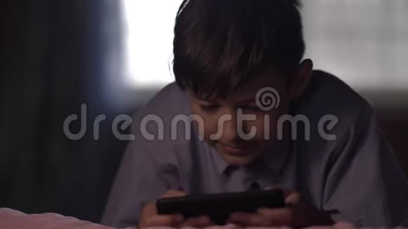 男孩躺在家里的床上晚上用电话视频的预览图